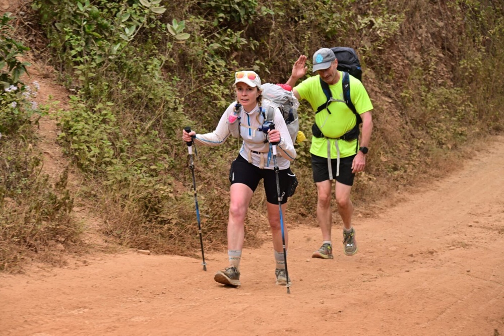 A person and person hiking on a dirt roadDescription automatically generated